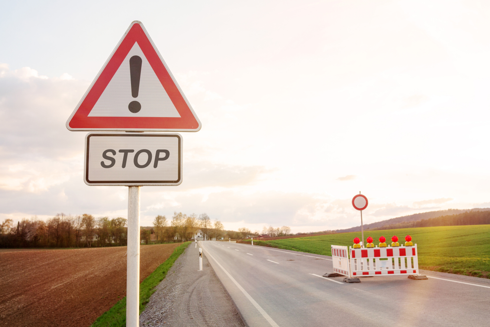 Road,block,with,street,sign,and,warning signs,lights,on,road