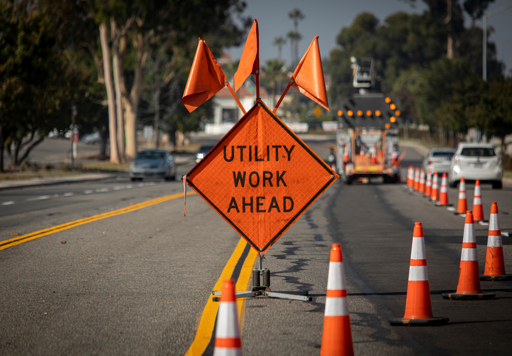 Traffic sign with flags reading utilitary work ahead with traffic